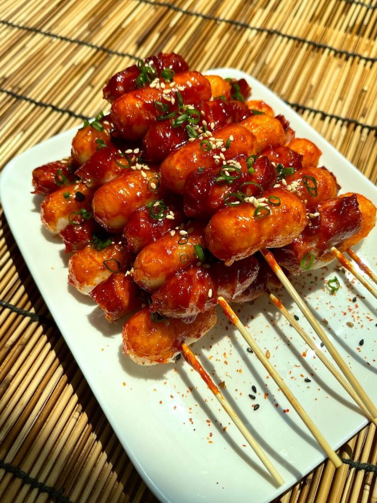 rice cake and sausage skewers on bamboo mat