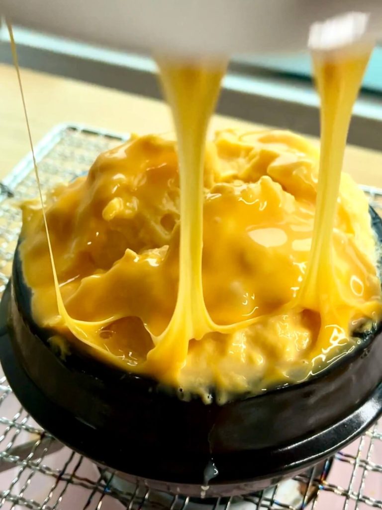 korean steamed eggs with melted cheese on top after lifting the lid