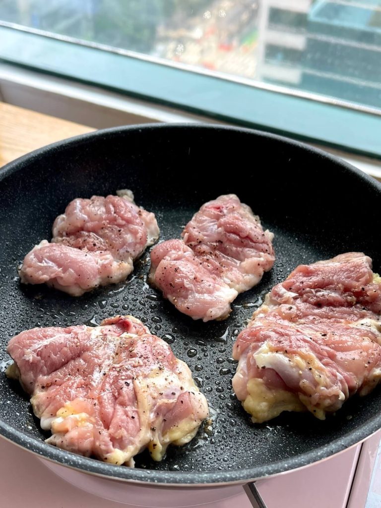 chicken thighs cooking in pan